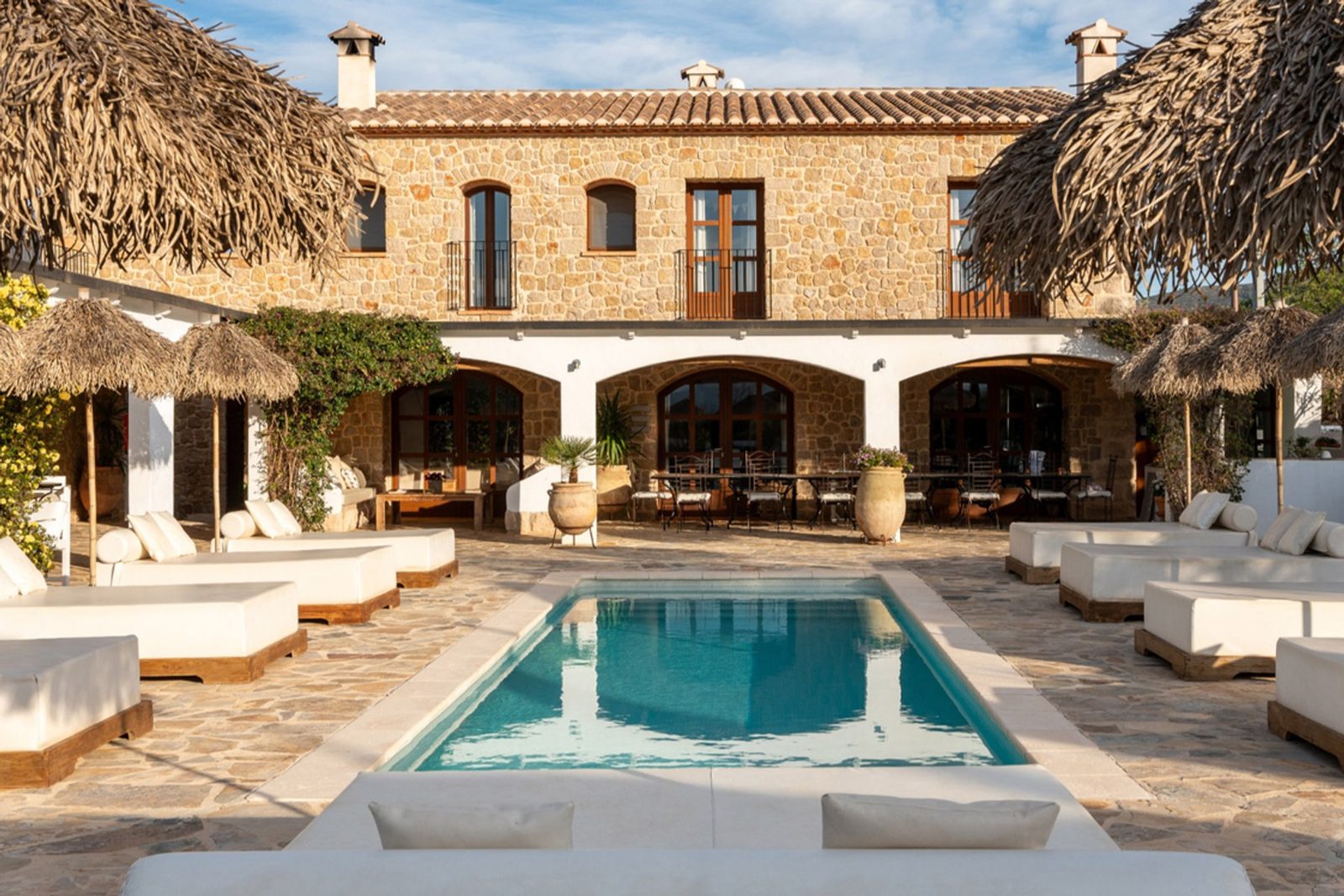 Stone finca courtyard with pool, loungers and thatched shade